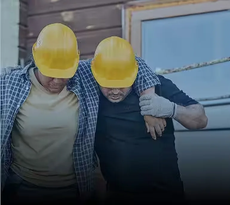 Two injured workers in hard hats leaving a job site