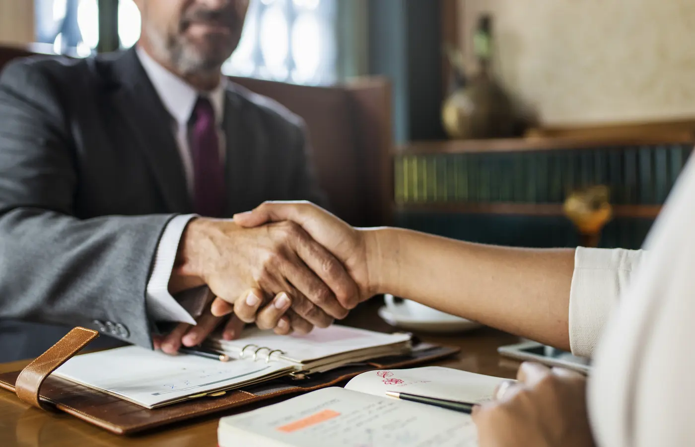 An attorney shaking hands with a client across a desk